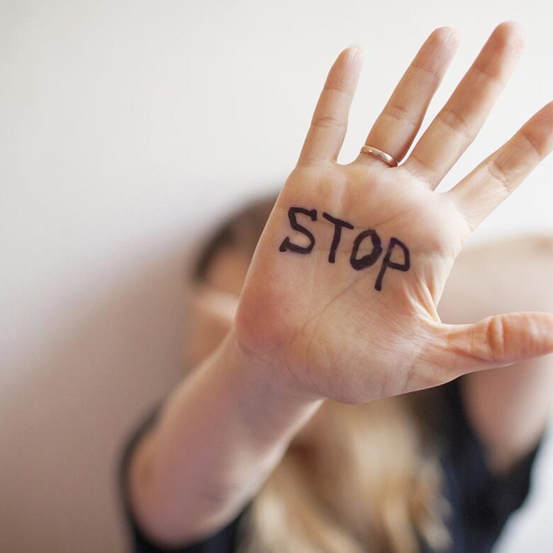 Woman shows palm with the inscription on the palm "Stop"