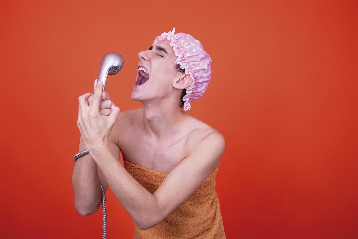 Funny guy is washing in the shower. Orange background.