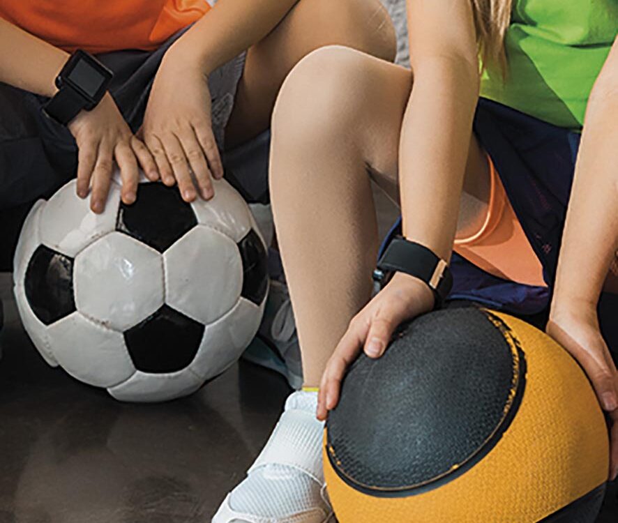 Cropped view of children sitting on step platforms with balls in