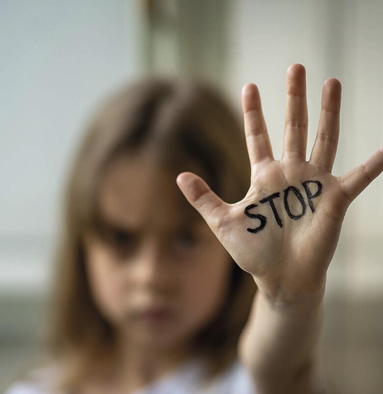 The child makes a stop gesture with his hand. Stop domestic and child abuse.